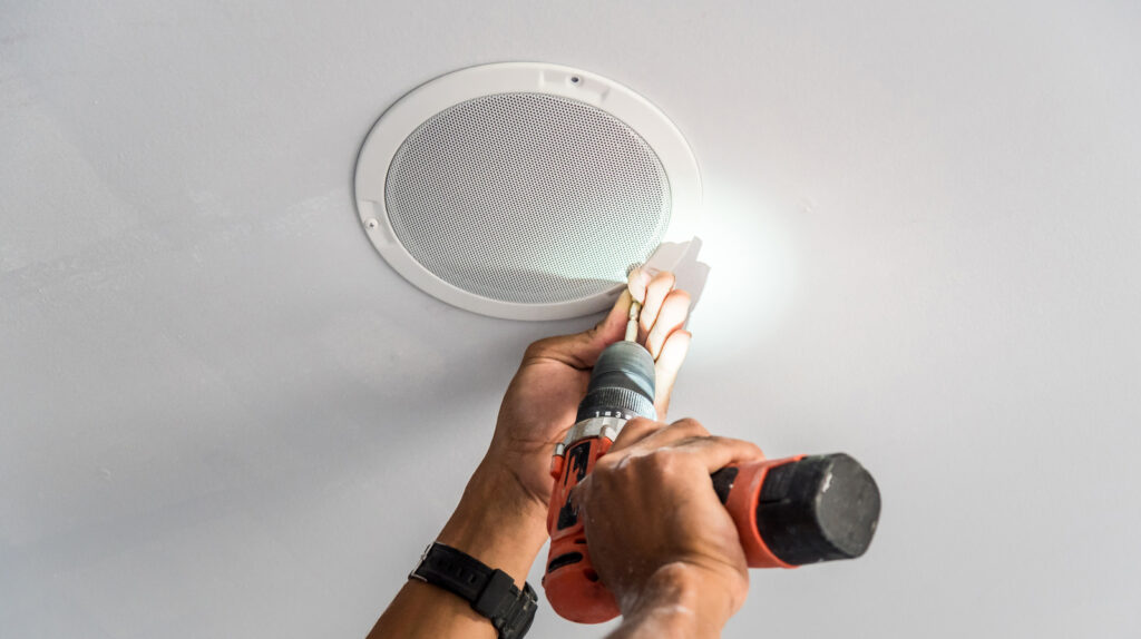 Technician,Is,Installing,Ceiling,Speaker,In,Hotel,By,Cordless,Battery
